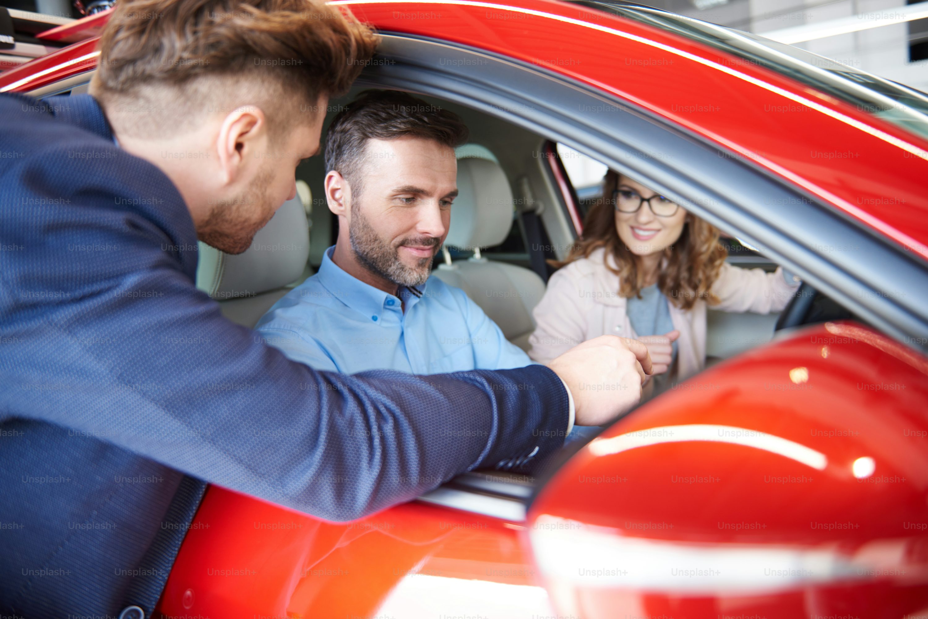 Car seller advising couple with vehicale