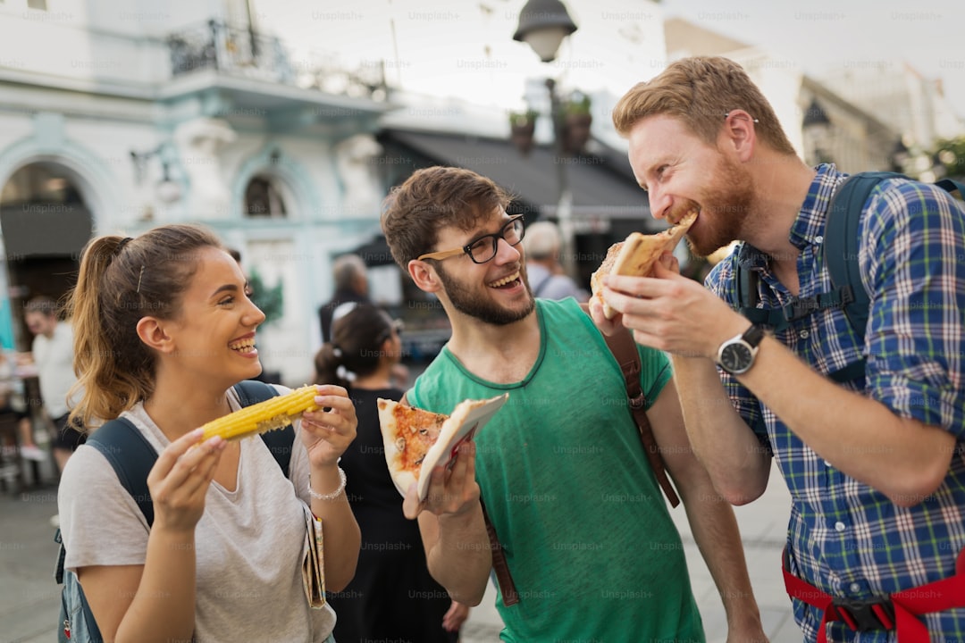 Happy group of friends eating pizza outdoors
