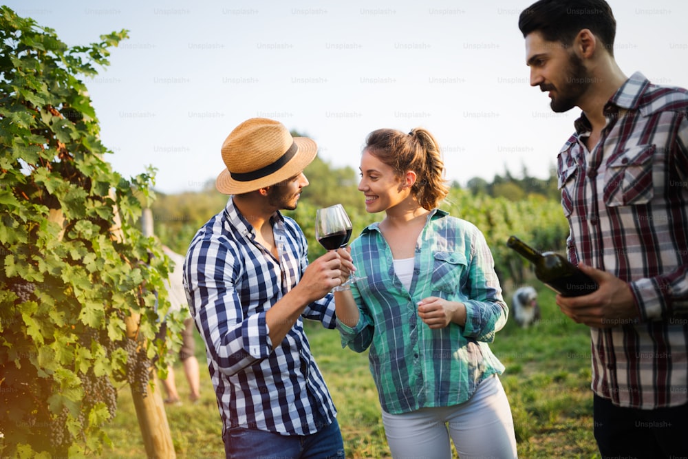 Happy wine growers tasting wine in vineyard