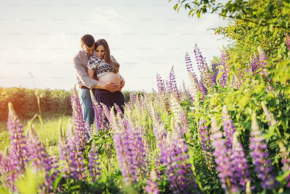 Happy beautiful girl pregnant with her husband outdoors on a background of flowers