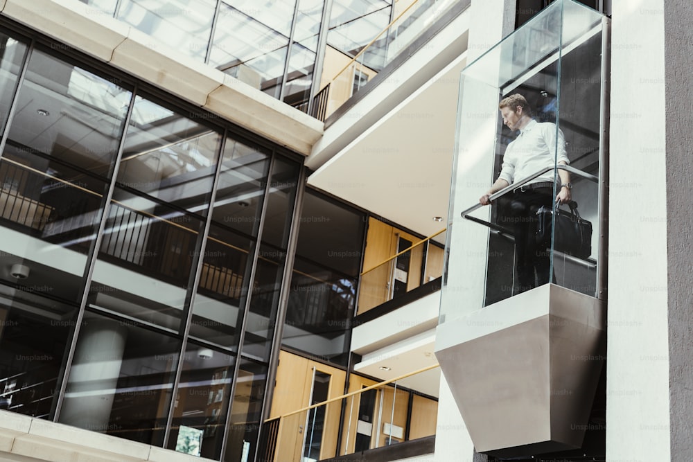 Businessman taking modern glass elevator to the upper floors