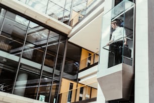 Businessman taking modern glass elevator to the upper floors