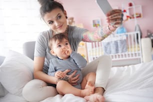 Jeune mère prenant un autoportrait avec un smartphone