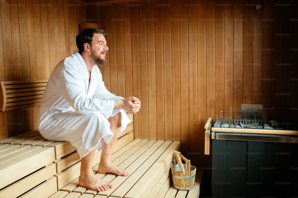 Homem bonito relaxando na sauna durante o fim de semana de bem-estar