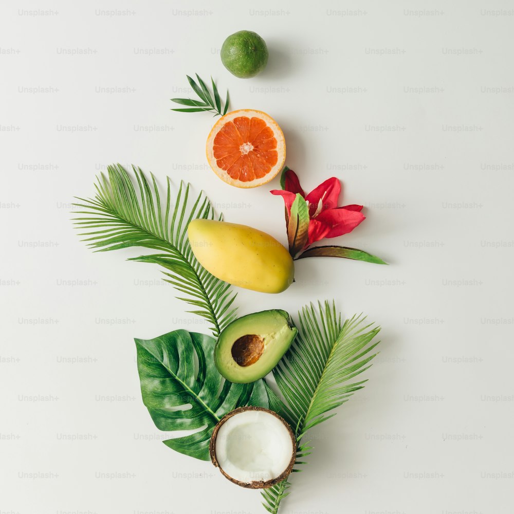 Kreatives Layout aus tropischen Sommerfrüchten und Blättern. Flache Liege. Food-Konzept.