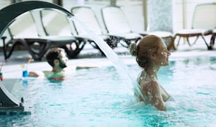 Mujer disfrutando de la hidroterapia y la corriente de agua en la piscina del balneario