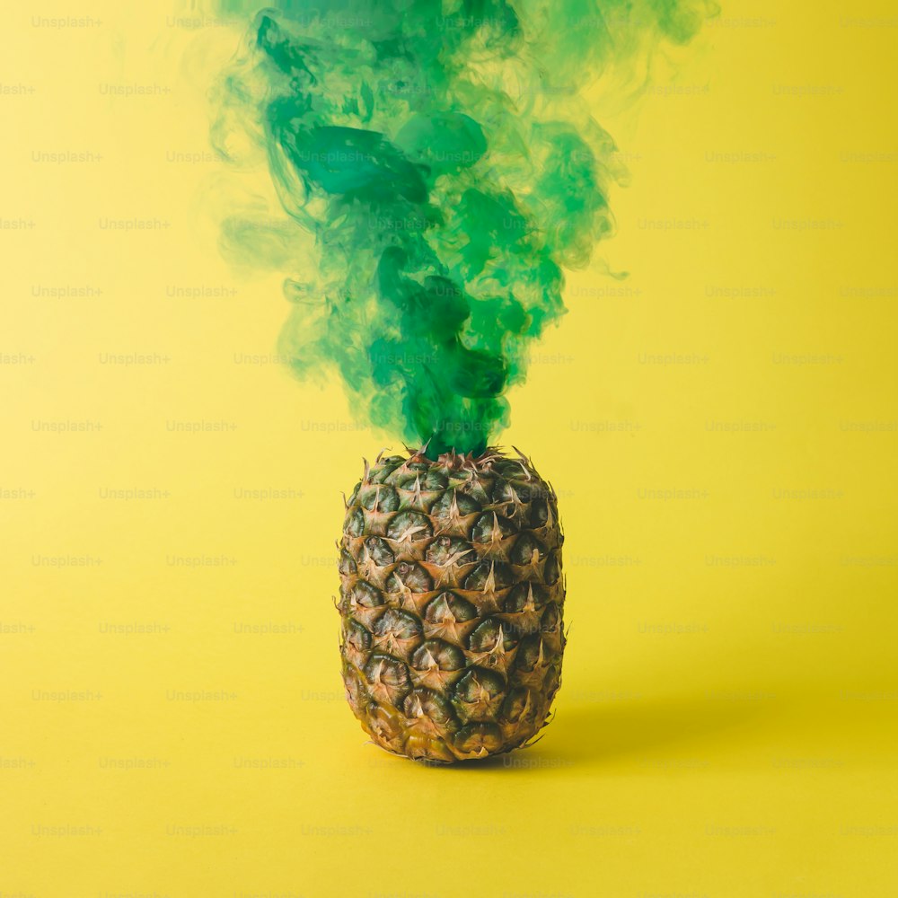 Pineapple with green smoke on bright yellow background. Friut concept.
