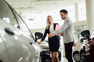 Salesperson selling cars at car dealership