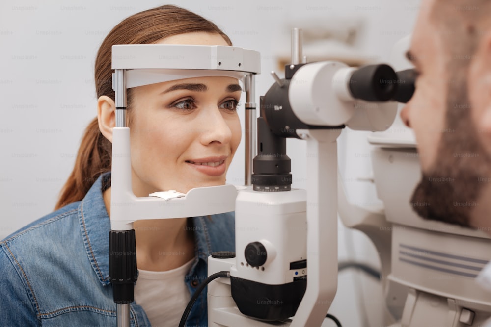 Doctors check up. Beautiful attractive pleasant woman resting her head on a special device and checking her eyesight while visiting an ophthalmologist
