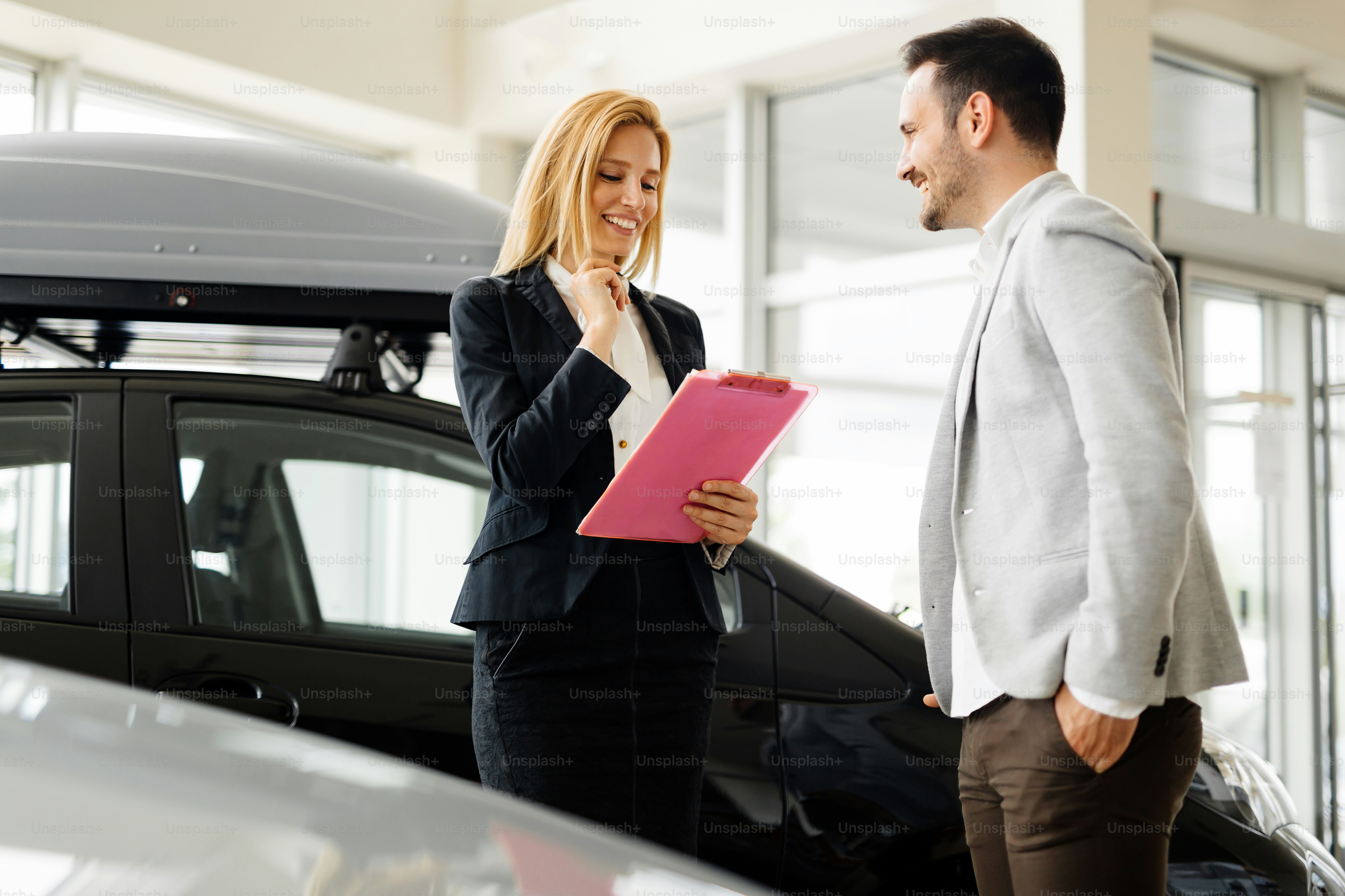 Professional salesperson selling cars at dealership to buyer
