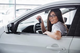 Mujer joven feliz cerca del coche con las llaves en la mano - concepto de compra de coche