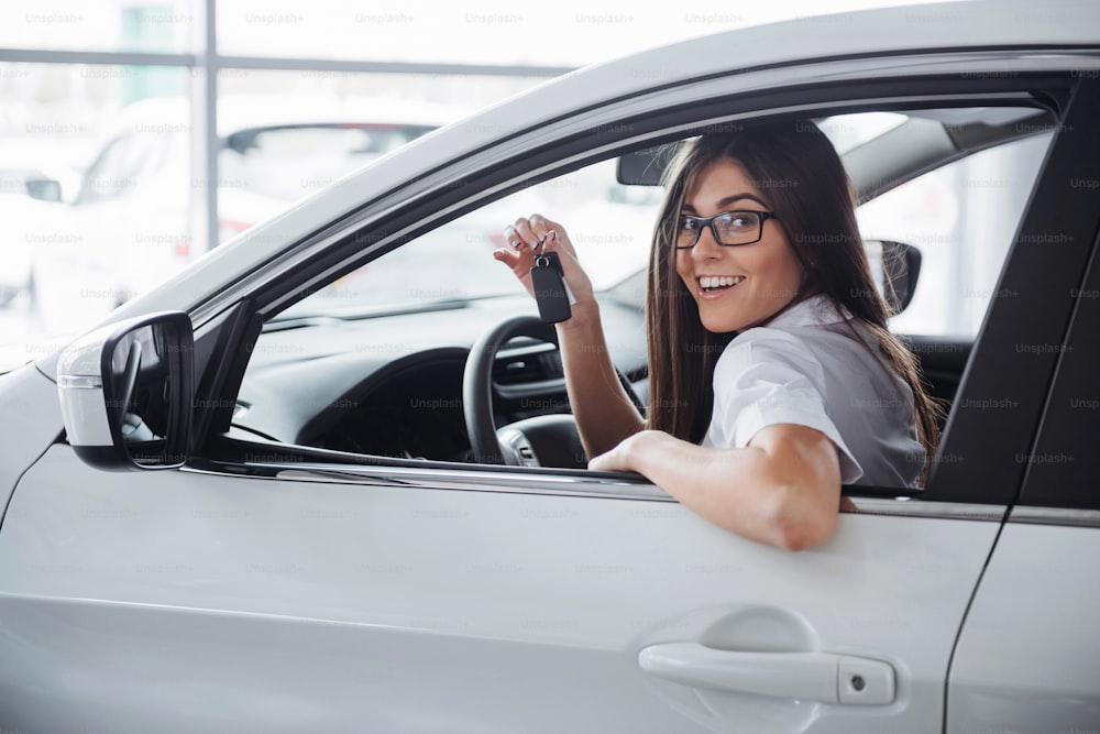 Mulher feliz nova perto do carro com chaves na mão - conceito de compra de carro
