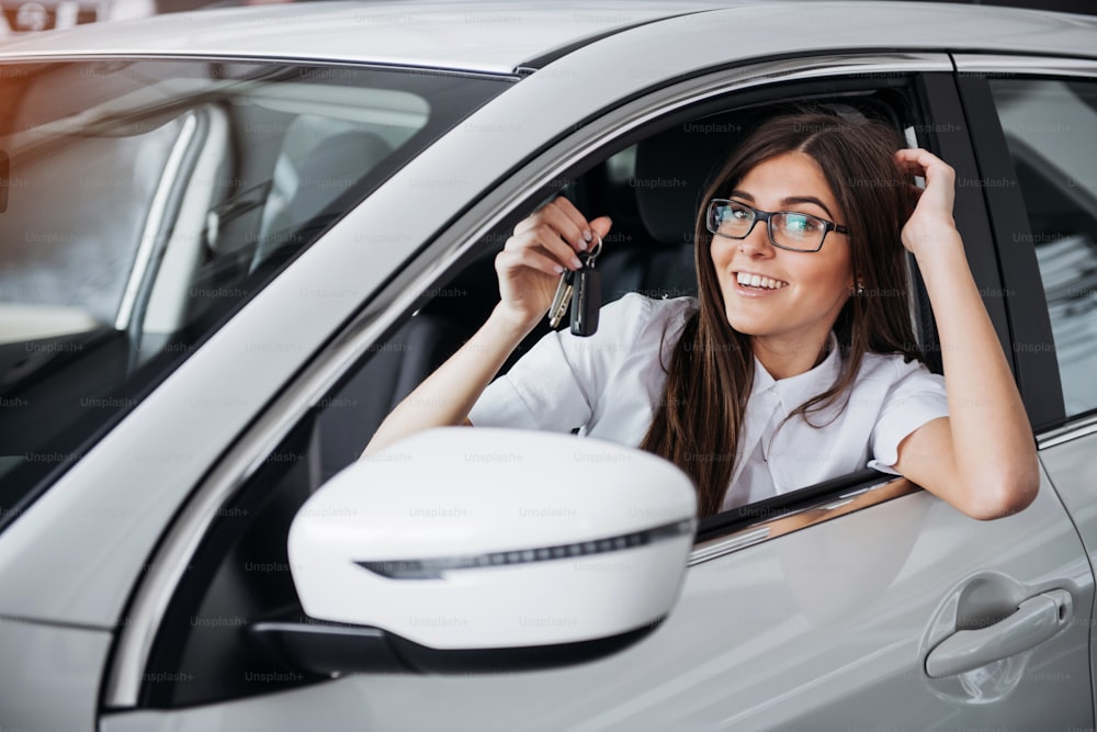 Giovane donna felice vicino all'auto con le chiavi in mano - concetto di acquisto di auto