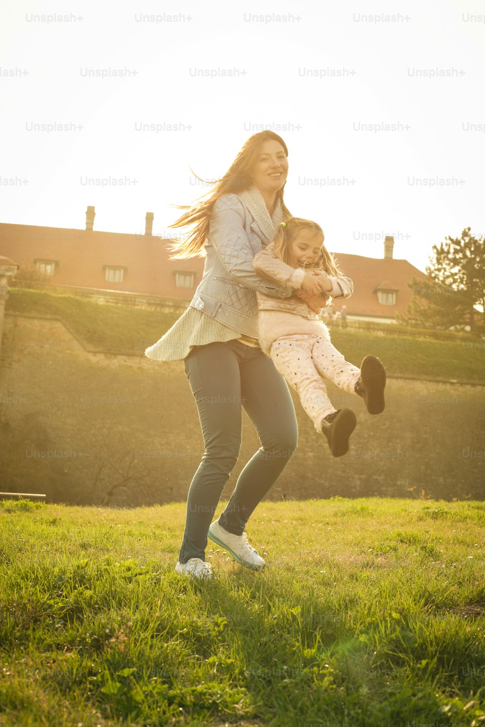 Mother playing with her daughter in the park. Looking at camera.