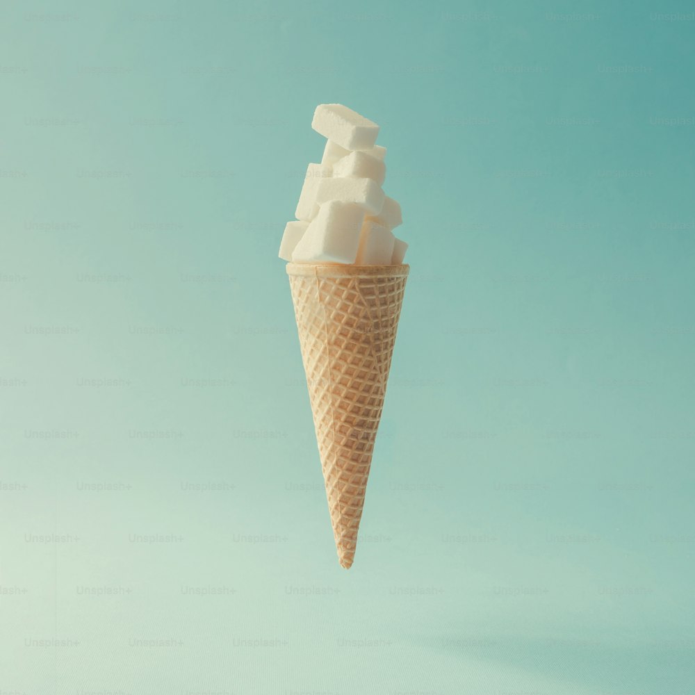 Ice cream cone with sugar cubes on bright blue background. Minimal food concept.