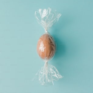 Egg wrapped like candy on bright blue background. minimal Easter concept.