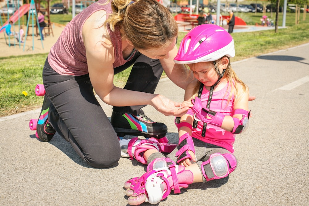 Mother consoling her daughter who fell while driving rollerblade.