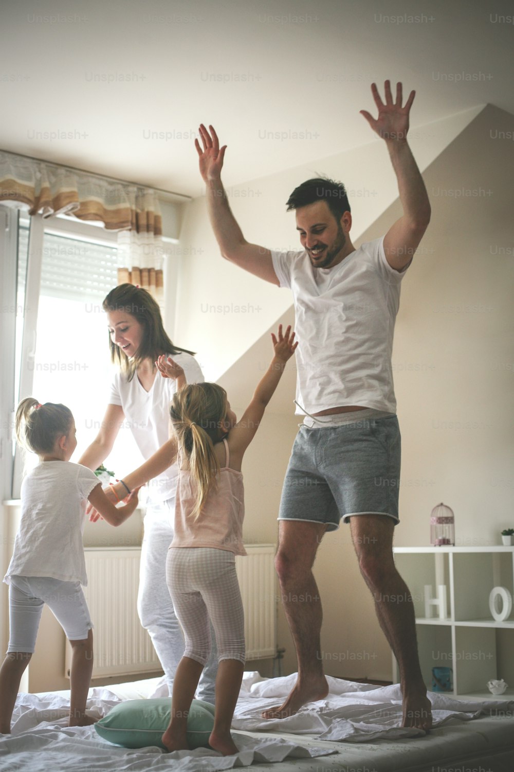 Family spending free time at home. Happy family jumping on bed together.