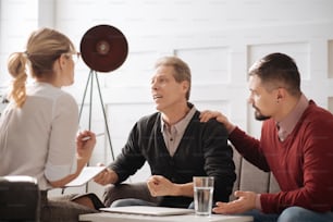 Personal problems. Emotional unhappy nice man clenching his fists and looking at the psychologist while trying to cope with his emotions