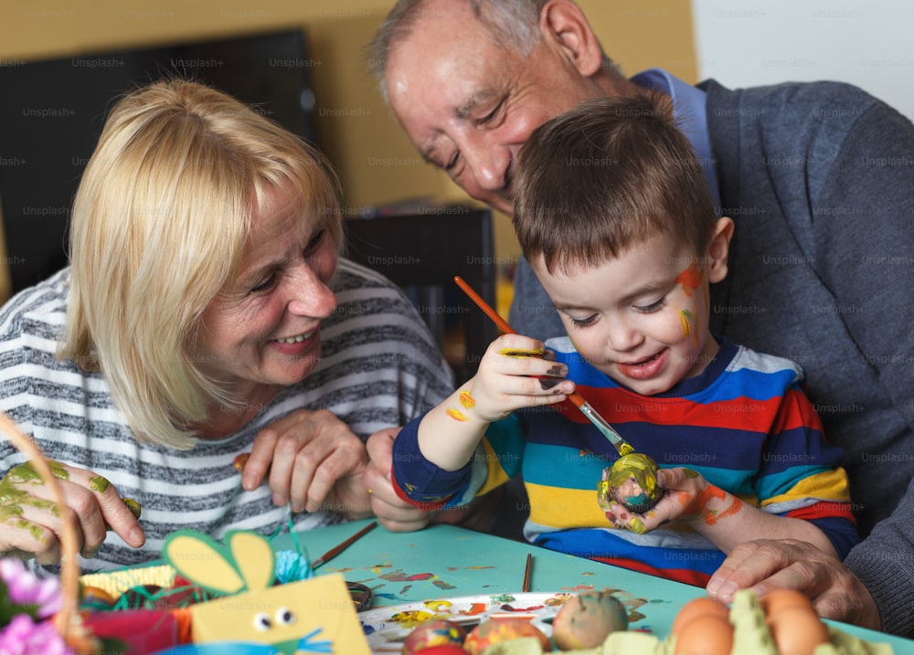 Grand-mère et grand-père avec petit-fils préparant des œufs pour Pâques.