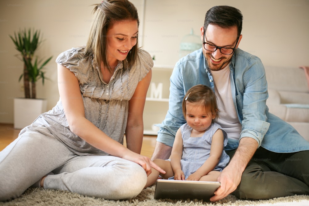 아기와 함께 바닥에 누워 있는 가족. �바닥에서 함께 디지털 태블릿을 사용하는 가족.