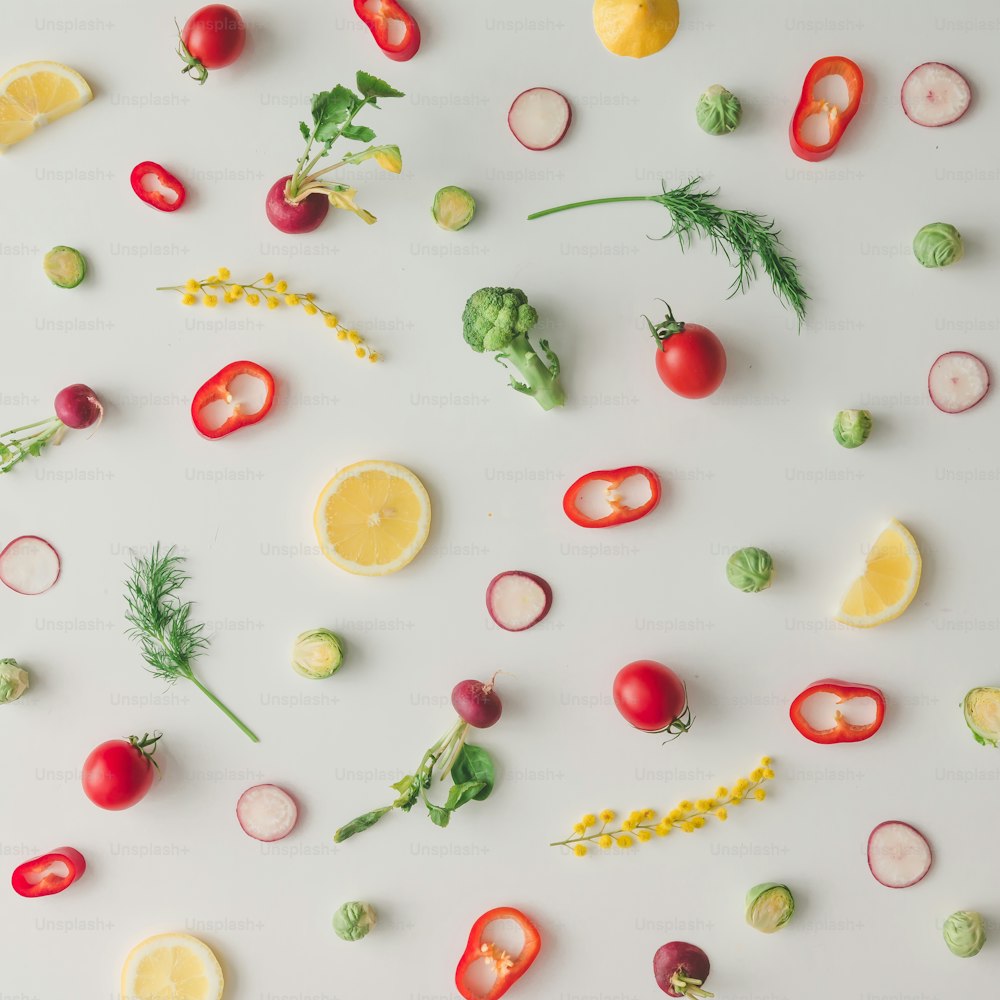 Colorful food pattern made of lemon, tomoatoes, red pepper and yellow flowers. Flat lay.