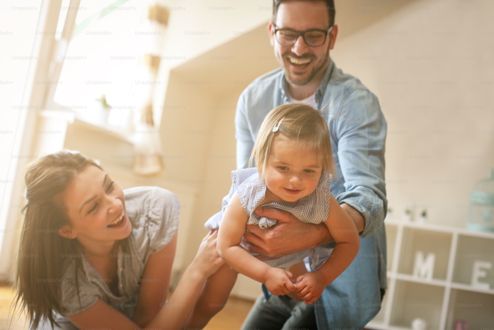 Happy family sitting  on floor with their little baby. Family spending time at home with their daughter. Father holding his little baby in hands