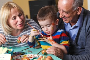 Grandmother and grandfather with grandson preparing eggs for Easter.