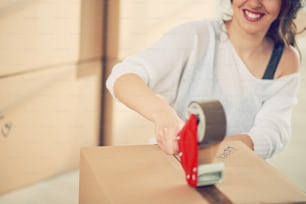 Caucasian girl using duct tape for packing boxes