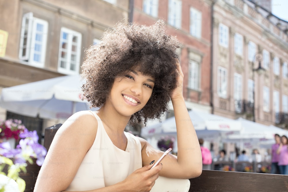 Belle jeune femme afro-américaine assise au café, journée ensoleillée.