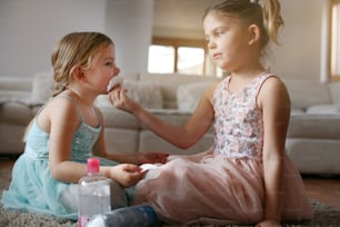 家で小さな妹の顔を掃除する小さな女の子。