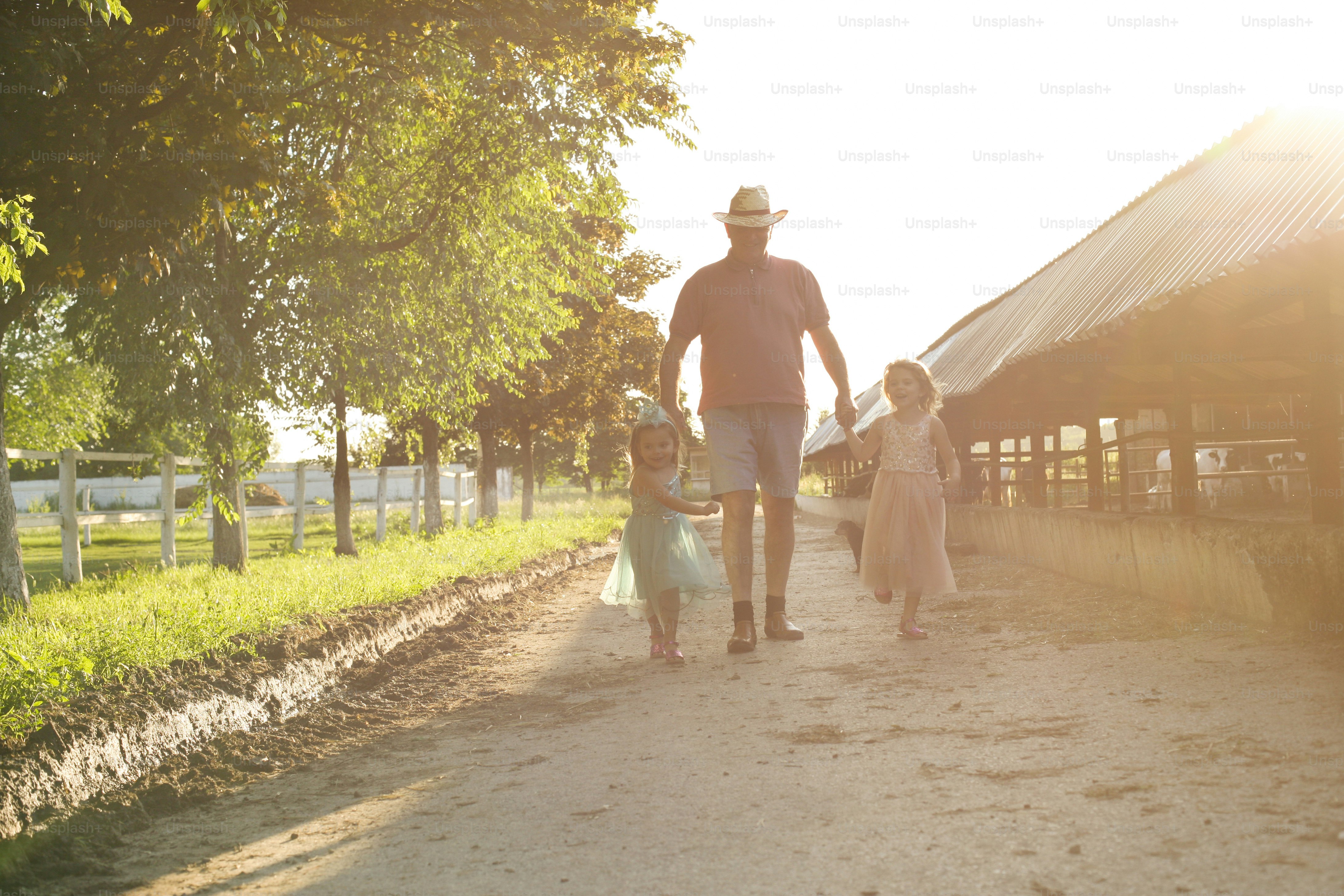 Due bambine e il nonno del villaggio, che camminano insieme e visitano la fattoria.