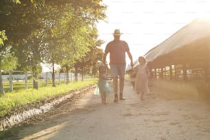 Two little girl and grandpa on the village, they walking together and visiting farm.