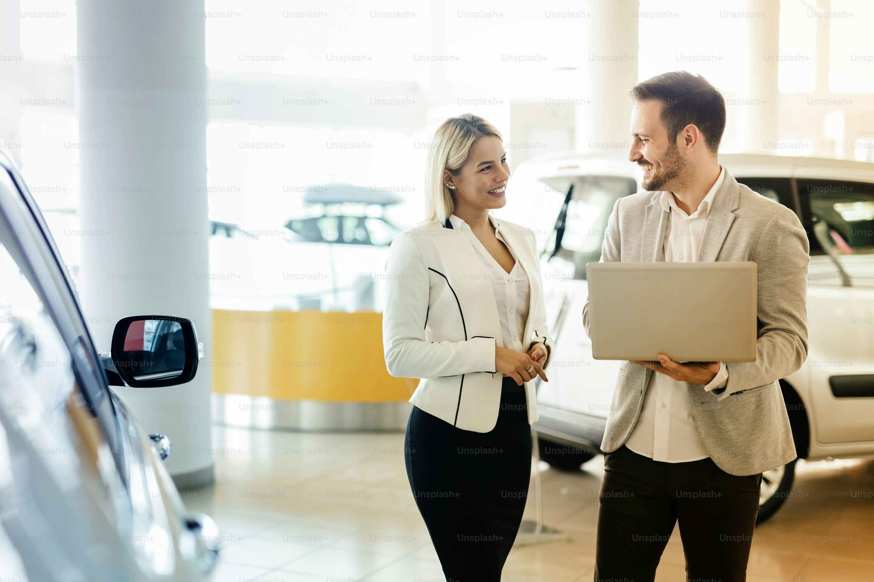 Professional salesperson selling cars at dealership to buyer