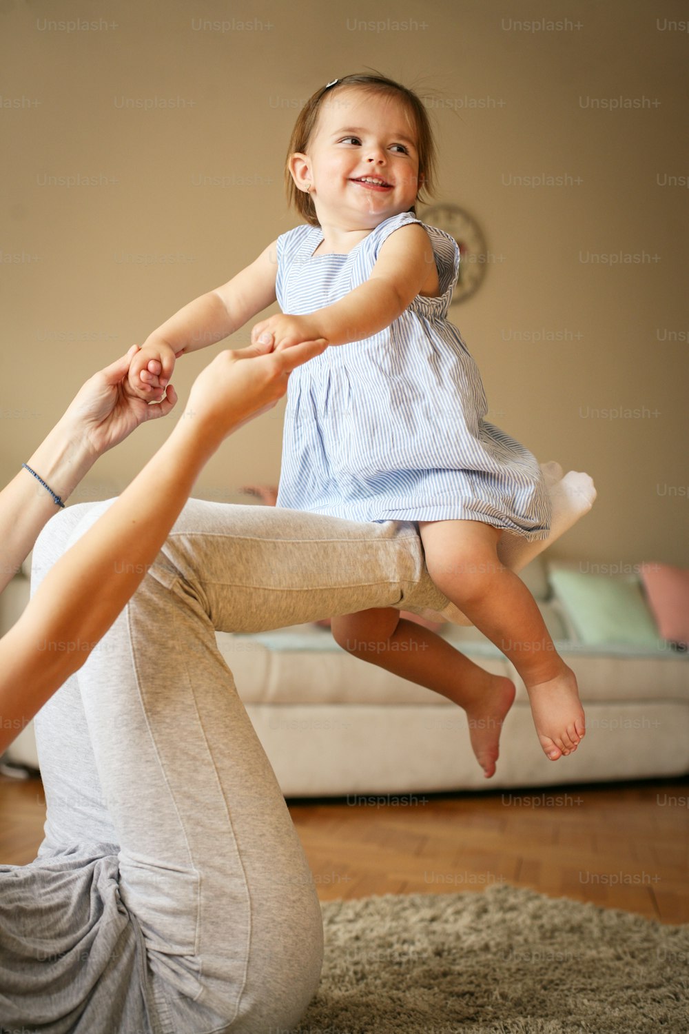 Jeune mère jouant avec sa petite fille sur le sol. Maman profitant de son temps libre avec son petit bébé mignon. Bébé assis sur les jambes de la mère.