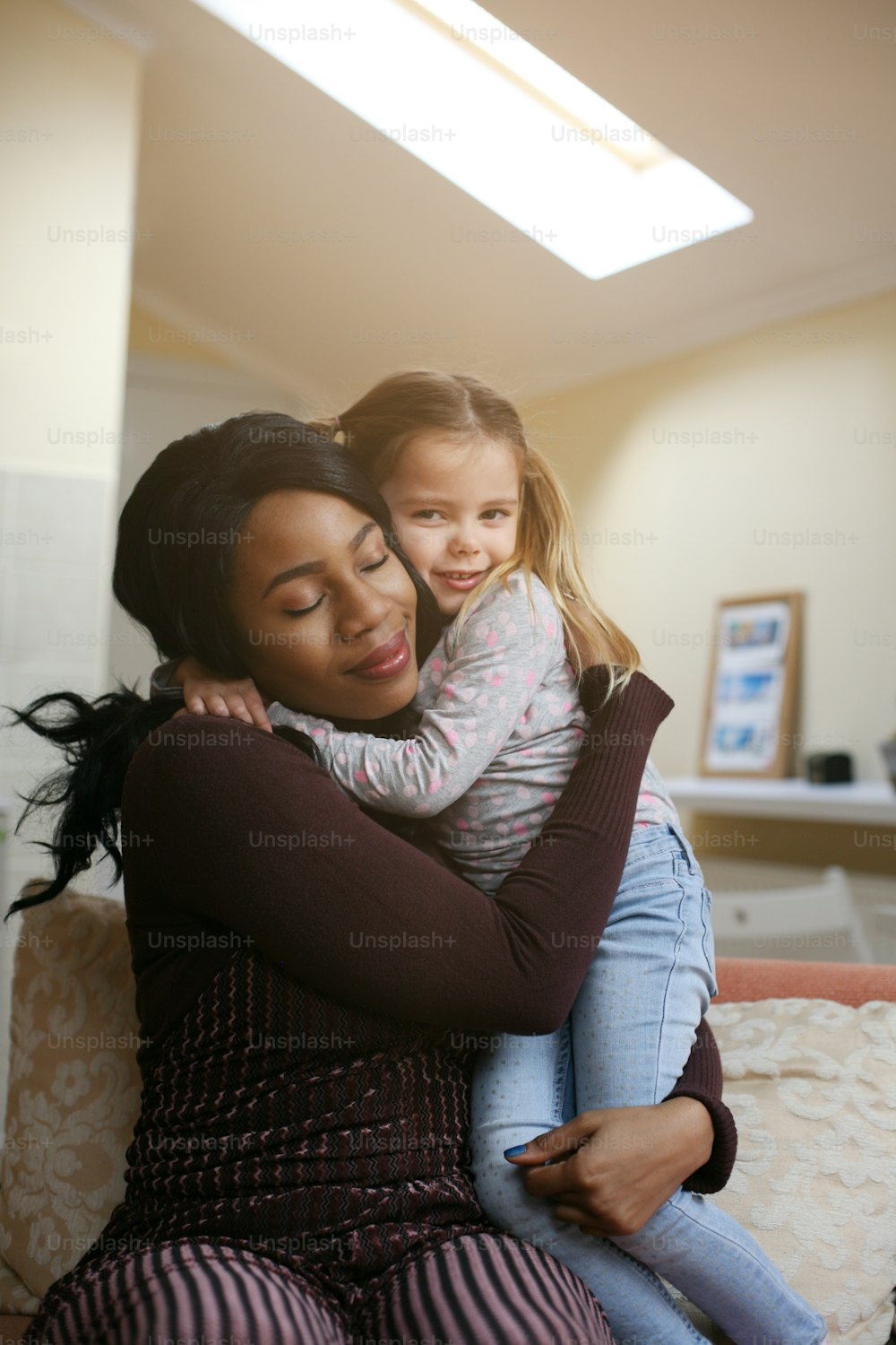 Afroamerikanische Frau spielt mit Mädchen. Frau umarmt ihre Adoptivtochter.