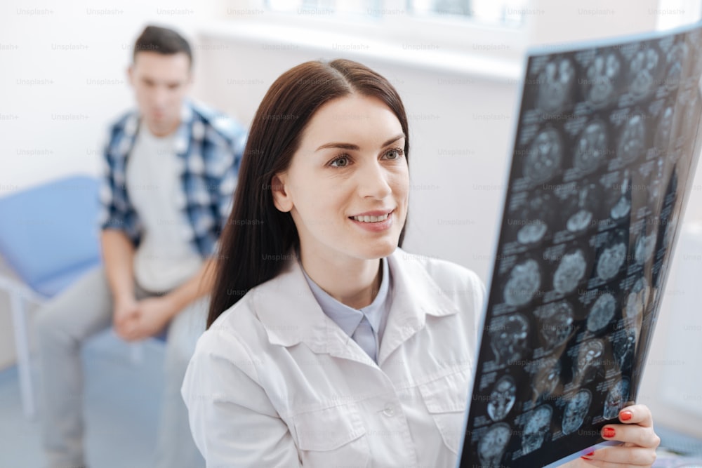 Mon patient est en bonne santé. Médecin joyeuse et ravie, regardant la photo radiographique et souriant en voyant l’amélioration