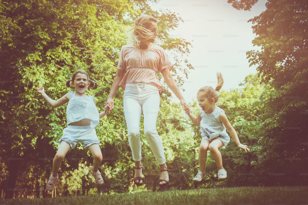 Mother with two daughter holding hands and jumping together.