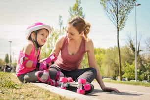 스케이트를 탄 후 어린 딸이 도로에 앉아 웃고 있는 어머니.