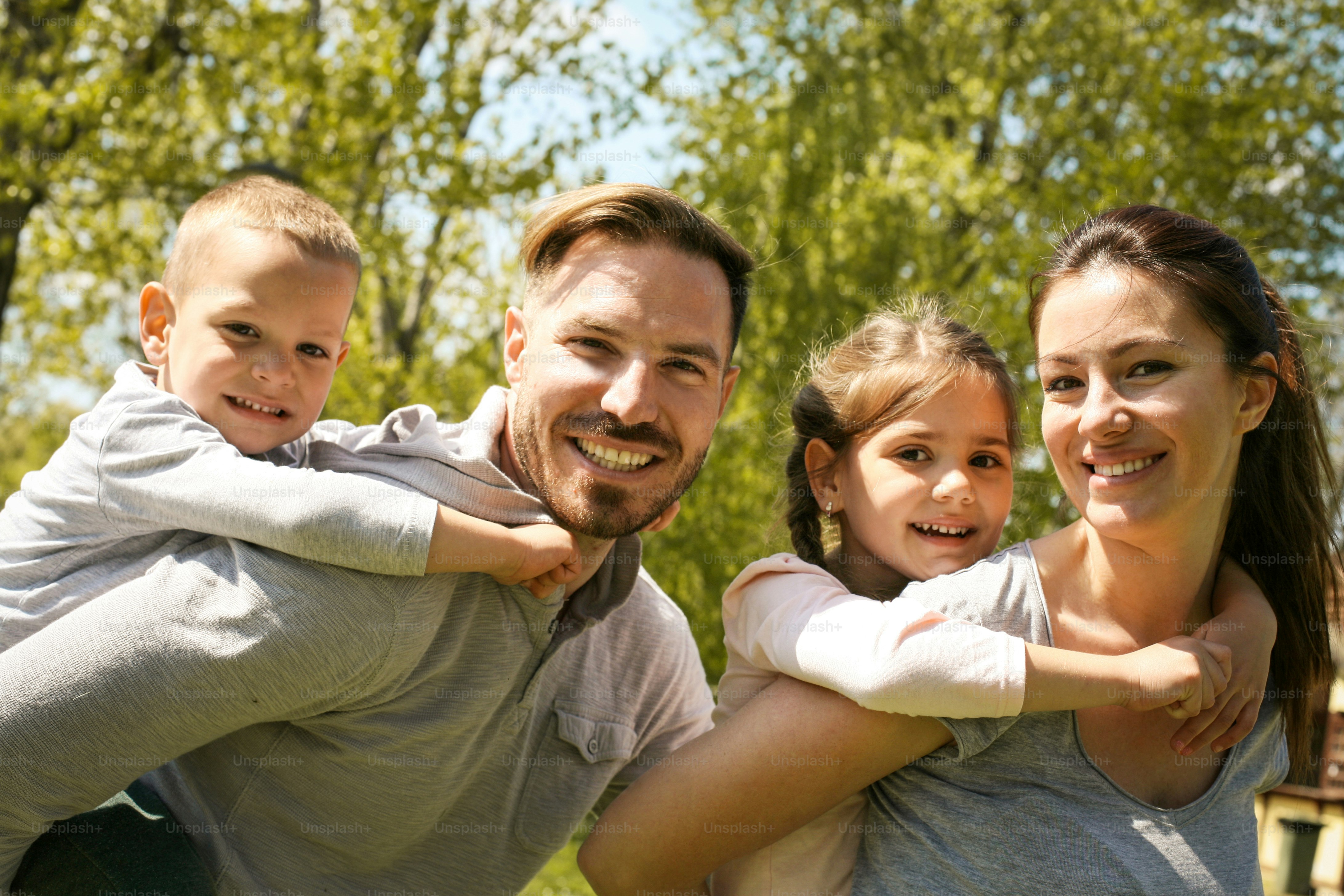 Parents playing with their children in the park. Looking at camera.\