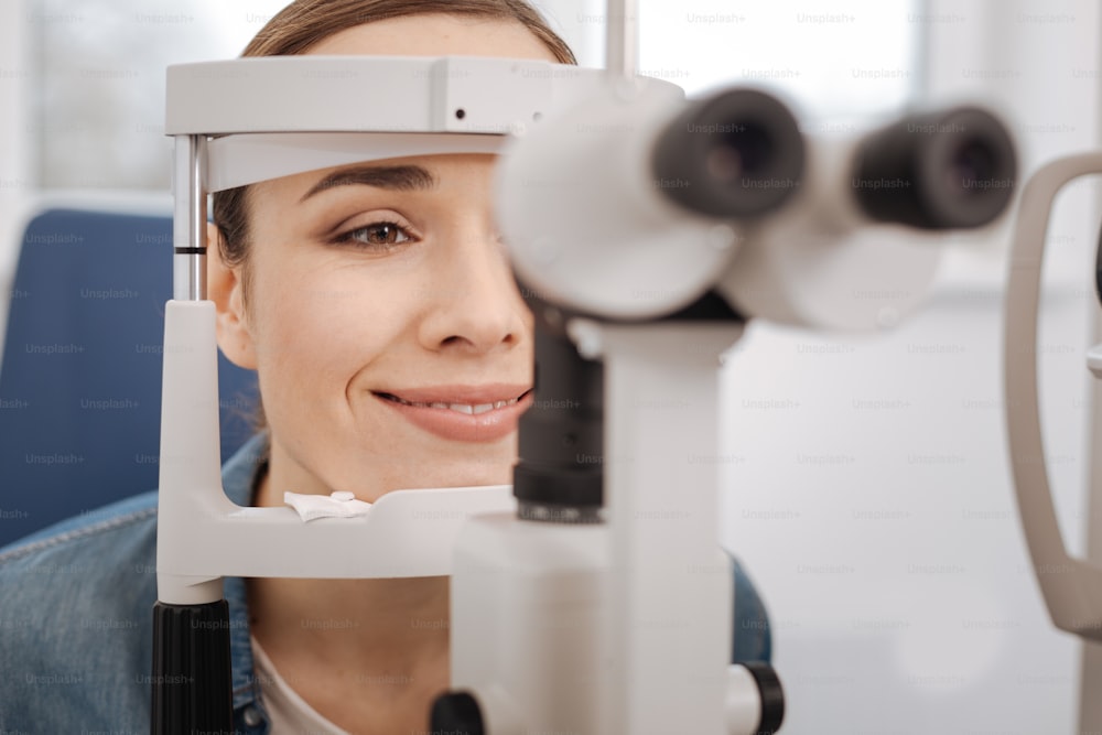 Médico check-up. Feliz bela mulher de boa aparência visitando um optometrista e tendo seus olhos verificados enquanto se preocupa com sua saúde
