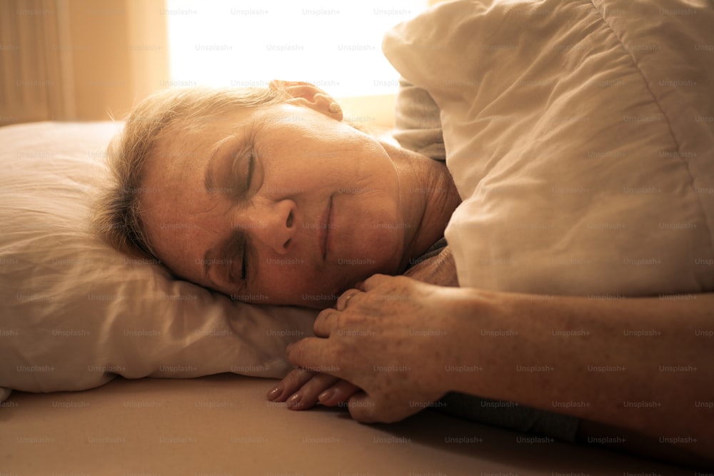 Senior woman sleeping in bed alone.