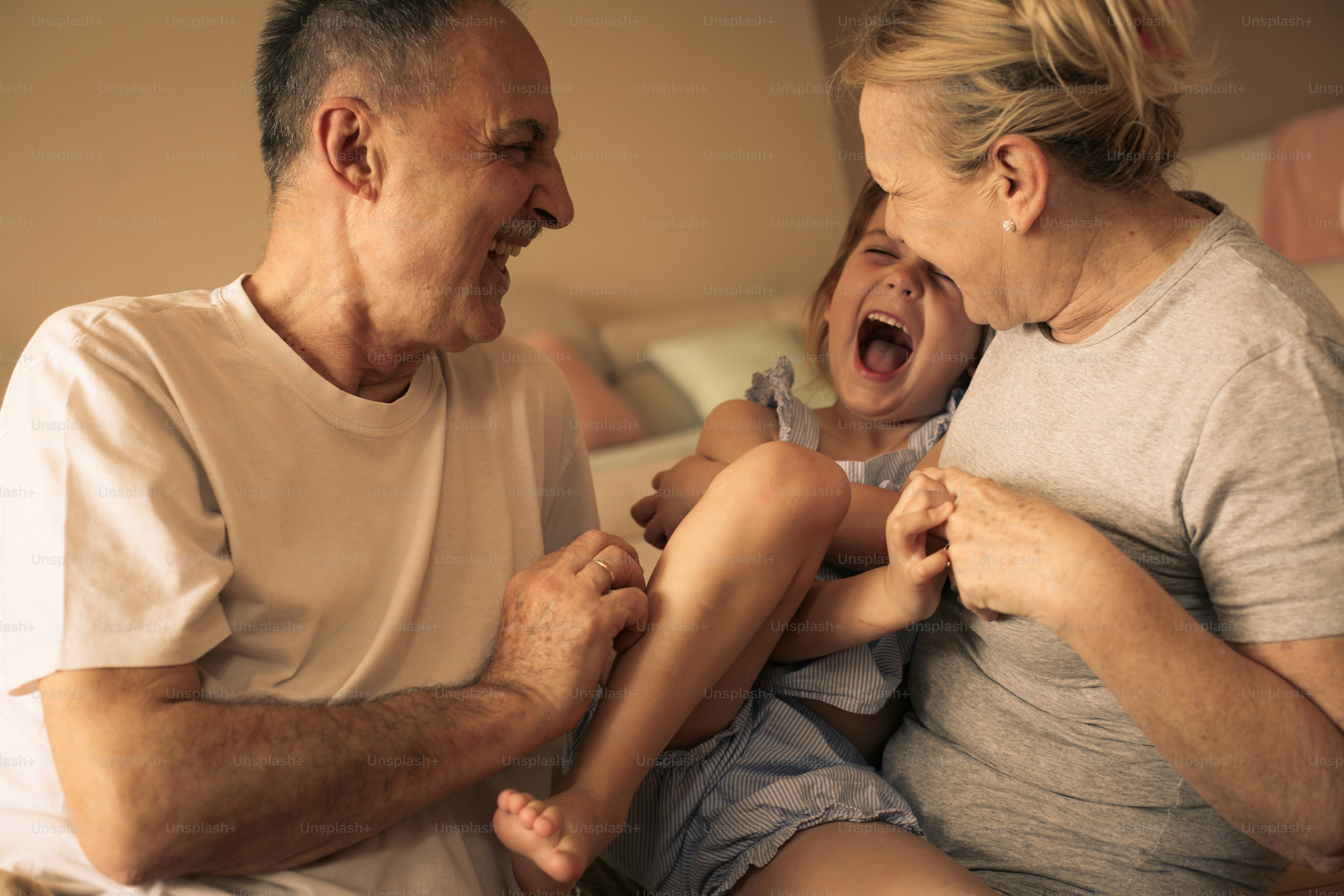 Grandmother and grandfather playing end enjoying with their granddaughter.