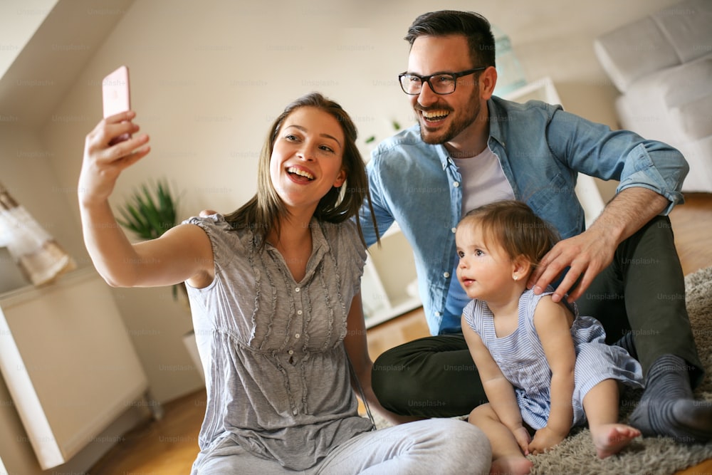 Glückliche Familie, die sich zusammen selbst aufbaut. Familie mit Smartphone.