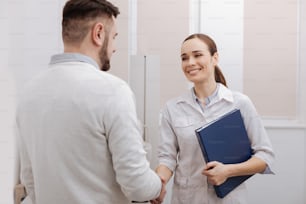 Friendly handshake. Nice positive delighted doctor and patient smiling and shaking hands while meeting each other