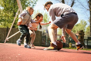 Single father with his children playing basket ball.