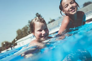 Divertimento subacqueo. Due bambine carine con gli occhialini che nuotano sott'acqua e si tuffano nel poll di nuoto. Sport e tempo libero.