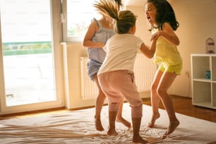 Little girls having fun together in bed. Little girls playing at home on bed.