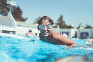 Diversão subaquática. Menina bonita com óculos nadando debaixo d'água e mergulhando na enquete de natação. Esporte e lazer.