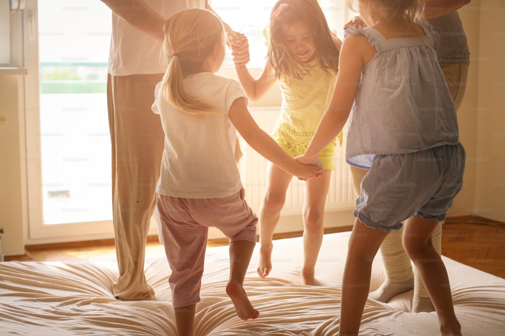 Abuela y abuelo junto a sus nietas bailando en la cama.